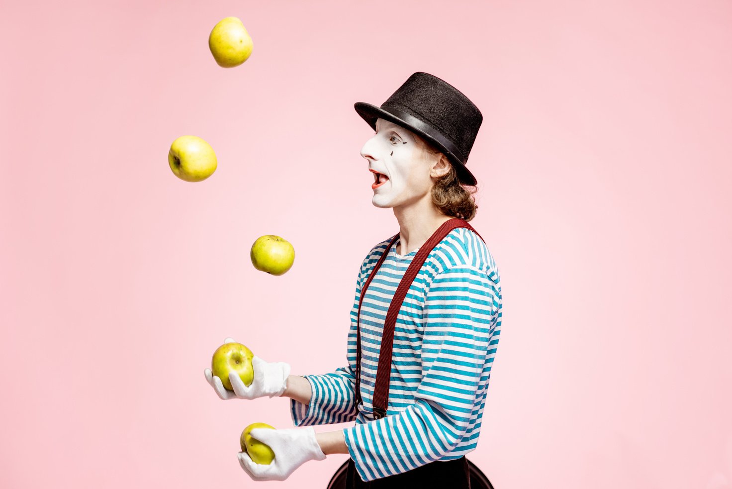 Pantomime Juggling with Apples on the Pink Background